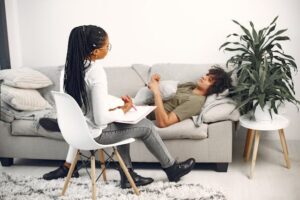 A picture of a traditional therapist talking to a client lying on a couch used to illustrate a FAQ about transformational coaching on Nick Hughes Coaching's website