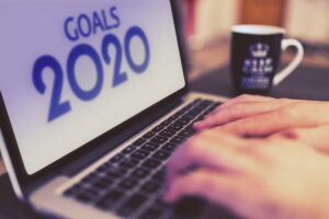 An image of someone typing their goals into a computer with a screen saying goals 2020. Used to illustrate a blog on Nick Hughes' coaching about new year's resolutions and how they fail